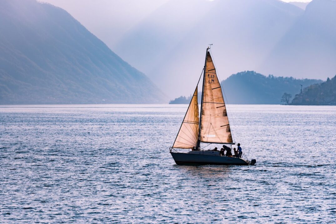a sailing boat in the sea surrounded by mountains