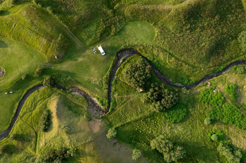 aerial view of land with trees and fields and car on it